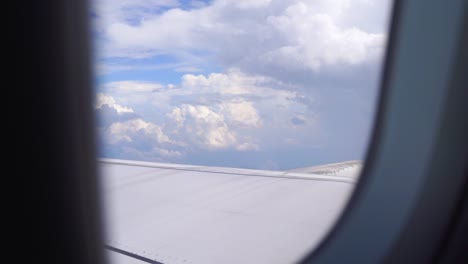 Slow-motion-view-outside-of-airplane-window-with-cloudy-blue-sky