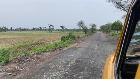 Shot-of-a-broken-road-in-a-village-from-the-seat-of-a-yellow-taxi-in-Bengal