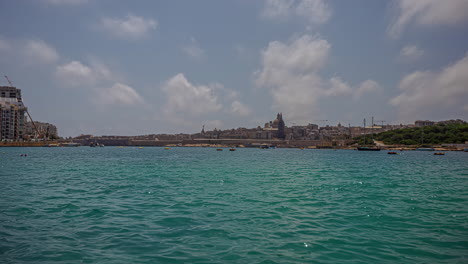 Timelapse-of-waterfront-port-city-of-Valletta,-Malta-on-sunny-day,-boats-in-water