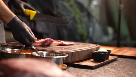 Pan-shot-of-chef's-hand-slicing-meat-to-be-grilled