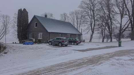 Timelapse-Wide-shot-of-country-house-with-cars-in-driveway-on-snowy-day