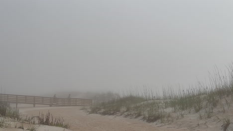 People-walking-across-ocean-walkway-into-foggy-beach-and-sand-dunes