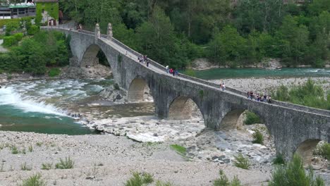 Gobbo-bridge-over-Trebbia-river-with-people,-Bobbio-in-Italy