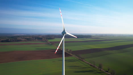 Wind-power-generator-turbine-spinning,-a-power-plant-in-an-open-green-field,-shot-from-drone