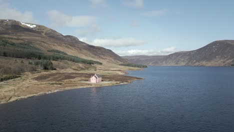 Aerial-view-of-the-famous-Pink-House-on-the-shores-of-Loch-Glass-in-the-Scottish-Highlands-on-a-sunny-spring-day