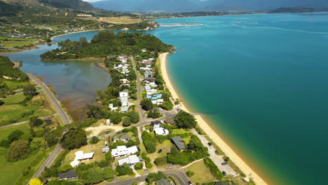 Aerial-tilt-up-flying-over-Ligar-Bay-beach-on-sunny-day,-New-Zealand