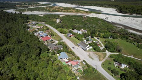 Homes-in-tiny-settlement-by-river-delta,-mountain-vista-reveal