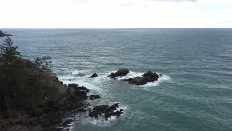 Still-aerial-view-of-moderate-waters-beating-against-rocks-in-the-middle-of-the-ocean