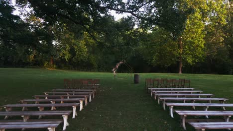 Fast-dolly-in-down-aisle-with-benches-and-chairs-at-wedding-location-in-park