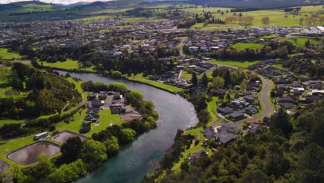 Taupo-Waste-Water-Treatment-Plant-and-housing-area-on-riverfront-Waikato-River,-New-Zealand---aerial,-sunny-day