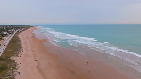 Aerial-orbit-around-playa-el-palmar-beach-in-Spain-with-long-waves,-sunny-day