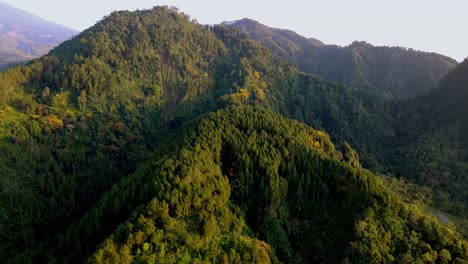 Tropical-forest-covered-mountain-slope,-ridgeline-and-valley,-drone-flyover
