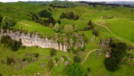 Aerial-View-Of-Rock-Wall-Formation-In-Mahoenui-With-Lush-Green-Field-In-Summer-At-King-Country,-North-Island-Of-New-Zealand