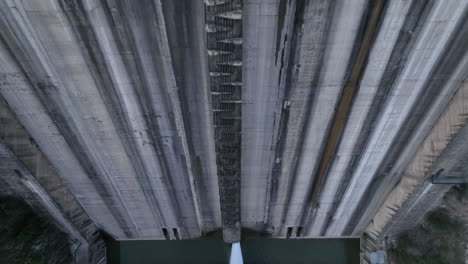 Aerial-view-looking-down-at-Sau-reservoir-concrete-wall-rising-over-hydroelectric-dam-structure