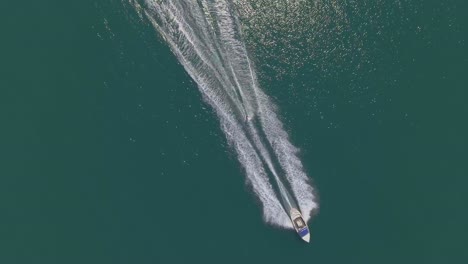 Aerial-top-down-view-deep-blue-sea,-wakeborder-pulled-by-a-speedboat