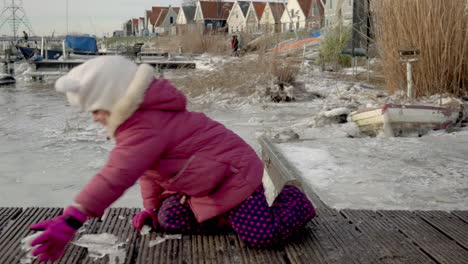 Cute-Dutch-girl-collecting-frozen-ice-crystals,-Durgerdam,-Amsterdam