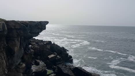 Cliff-by-the-sea-with-a-fishing-rod-among-the-rocks-on-a-gray-day