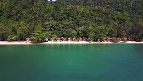 Dramatic-aerial-view-flight-Cabins-huts-Bungalow-accommodation-on-jungle-white-sandy-beach-island-koh-chang-thailand-2022