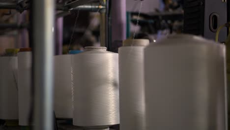 Work-machine-manufacturing-socks-tights---Close-up-shot-of-Spools-with-white-thread-at-rewinding-machine-video
