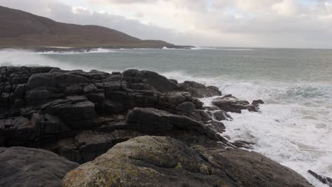 Slow-motion-shot-of-large-waves-crashing-over-the-rocks-during-a-storm-in-the-bay-by-Tangasdale-beach,-near-Castlebay-on-the-Isle-of-Barra