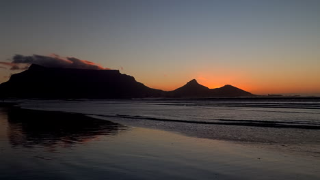 Atemberaubende-Kapstadt-Tafelberg-Strandlandschaft,-Tieforangefarbener-Abend,-Später-Sonnenuntergang,-Südafrika,-Ebbe,-Unglaubliche-Küstenlinie,-Tagesende,-Frieden,-Zeitlupenschwenk-Nach-Links