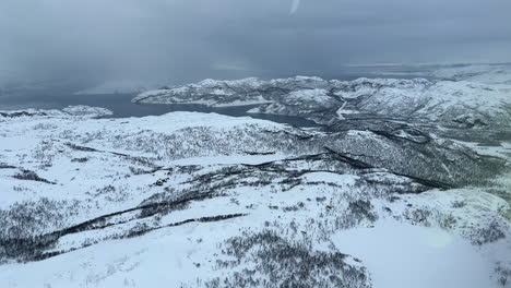 Aerial-view-of-a-snow-storm-coming-in-from-the-ocean-towards-the-mainland-in-Northern-Norway,-Finnmark