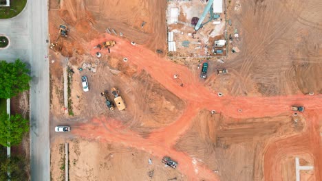 An-aerial-drone-4k-top-down-birds-eye-view-of-a-construction-site-with-a-crane-holding-2-safely-harnessed-construction-workers