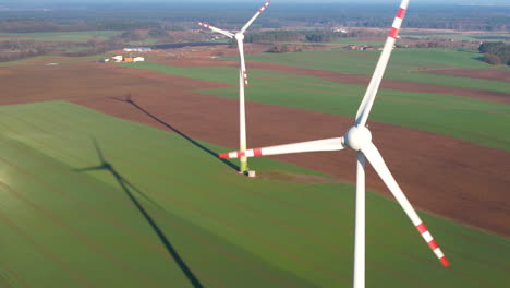 Revealing-aerial-view-of-two-industrial-wind-turbines-generating-wind-energy-on-a-green-crops-field-in-Polish-rural-area