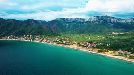 Aerial-View-Of-Golden-Beach-With-Towering-Mountain-Peaks,-Beautiful-Beachfront-And-Lush-Vegetation,-Vivid-Colors,-Thassos-Island,-Greece,-Europe