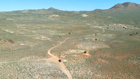 Luftaufnahme-Eines-Roten-Lastwagens,-Der-Im-Frühling-Abseits-Der-Straße-Durch-Die-Wüste-Von-Nevada-Fährt,-Mit-Leuchtendem-Grün-Und-Buntem-Sand