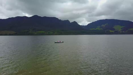 Motorboat-on-a-lake-in-cloudy-weather,-aerial-push-in