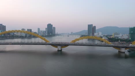 Aerial-of-iconic-Dragon-Bridge-Cau-Rong,-traffic-and-city-skyline-during-sunset-in-Danang,-Vietnam