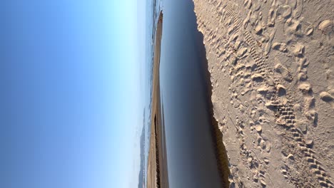 Mouth-of-a-river-that-crosses-the-beach-in-the-direction-of-the-sea,-vertical-view-for-mobile
