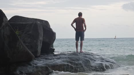 Rücken-Eines-Mannes,-Der-Auf-Einem-Felsen-Mit-Tosenden-Wellen-Am-Strand-Von-Dam-Trau-In-Vietnam-Steht