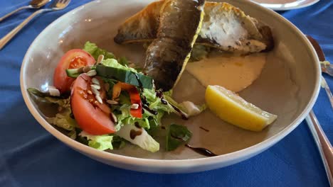 Baked-trout-with-salad-and-lemon-served-at-a-restaurant-in-Iceland-with-close-up-video