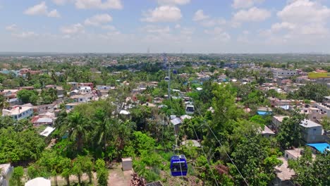Aerial-flyover-cable-car-over-green-city-of-Los-Alcarrizos-near-Santo-Domingo-during-sunny-day