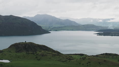 Ein-Ruhiger-Blick-Auf-Einen-Friedlichen-See,-Umgeben-Von-Grünen-Sanften-Hügeln-Und-Nebligen-Bergen-In-Neuseeland