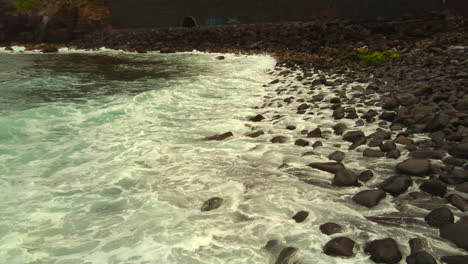 Close-up-video-of-the-waves-on-the-shore-pounding-against-the-black-rocks