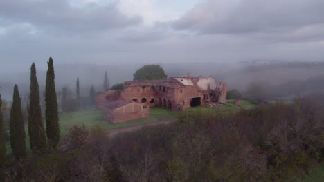 Reveal-shot-of-empty-deserted-farm-house-building-in-rural-Italy,-aerial