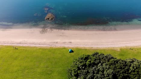 Tent-close-to-the-sandy-beach-aerial-reveal-of-beautiful-scenic-coastal-scenery,-Summer-sunny-day-at-Bay-Of-Islands,-New-Zealand