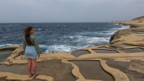 Eine-Dame-Steht-Auf-Den-Klippen-Der-Insel-Malta-Und-Blickt-Auf-Das-Meer