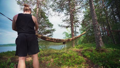 Hiker-Setting-Up-A-Camping-Hammock-With-Mosquito-Net-At-The-Forest