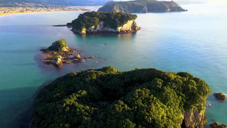 Donut-shape-island,-New-Zealand-coastal-scenery,-Whangamata-township-reveal