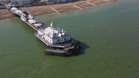 Flying-around-Eastbourne-Pier,-sea-front-and-beach