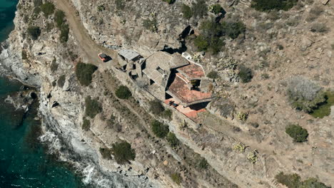 Villa-with-view-to-lake-or-ocean-on-steep-cliff-side,-aerial-drone-view