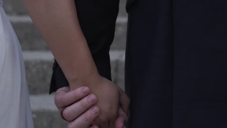 Close-up-newlywed-couple-holding-hands-walking-up-stone-church-steps-to-wedding-ceremony
