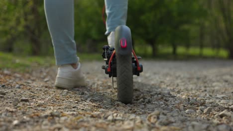 Low-angle-close-up-of-electric-scooter-on-a-gravel-path