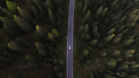 Aeriall-view-above-a-car-on-a-forest-road,-sunset-in-Dolomites,-Italy---birdseye,-drone-shot