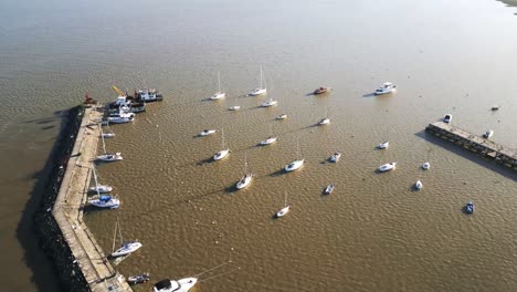 Aerial-view-flying-over-yachts-moored-on-Colonia-del-Sacramento-sunlit-marina-on-the-Uruguay-coastline