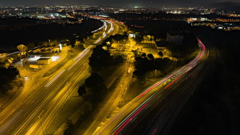 Time-lapse-aerial-view-illuminated-traffic-headlights-rush-hour-driving-busy-downtown-highway-at-night